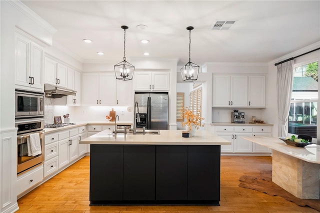 kitchen with decorative light fixtures, white cabinets, stainless steel appliances, and a kitchen island with sink