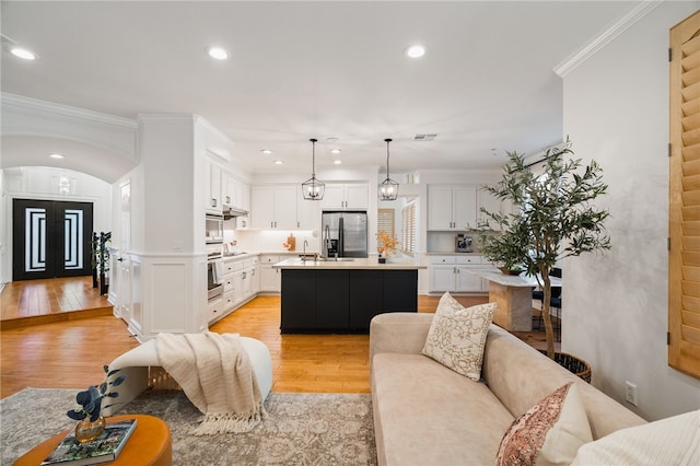 living room with sink, light hardwood / wood-style flooring, crown molding, and a chandelier