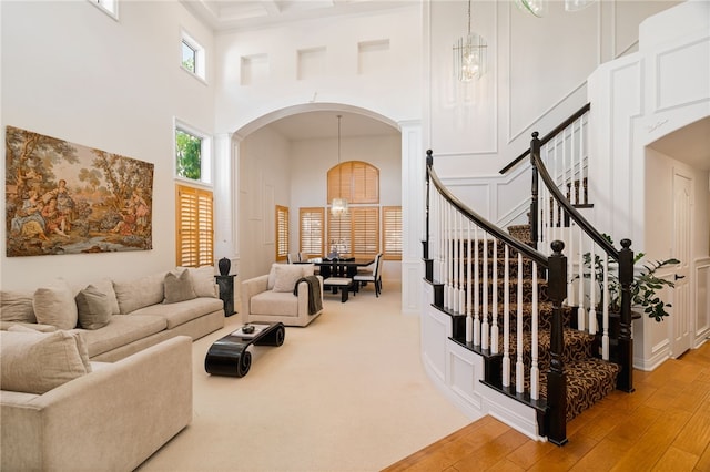 living room featuring light wood-type flooring, an inviting chandelier, and a high ceiling