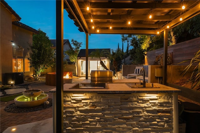 patio terrace at dusk featuring central AC, an outdoor kitchen, area for grilling, and sink