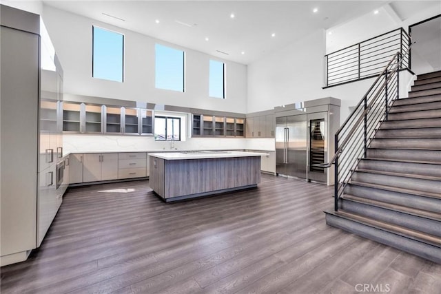 kitchen featuring dark wood-type flooring, a high ceiling, gray cabinets, and a kitchen island