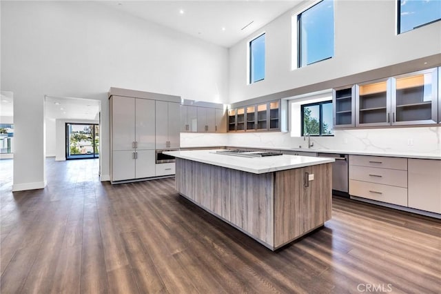 kitchen featuring a high ceiling, tasteful backsplash, gas stovetop, dishwasher, and a kitchen island