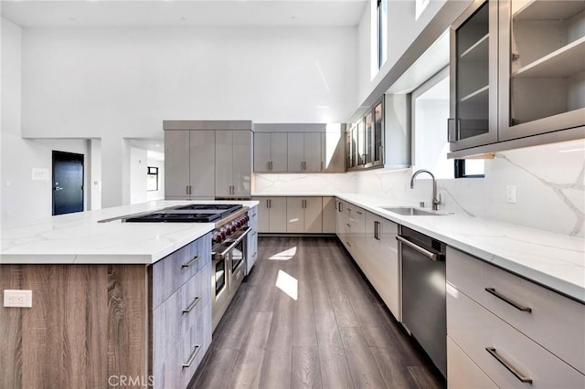 kitchen with light stone countertops, stainless steel dishwasher, backsplash, and sink