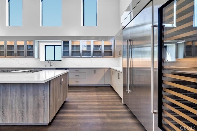 kitchen featuring appliances with stainless steel finishes, a towering ceiling, backsplash, and sink