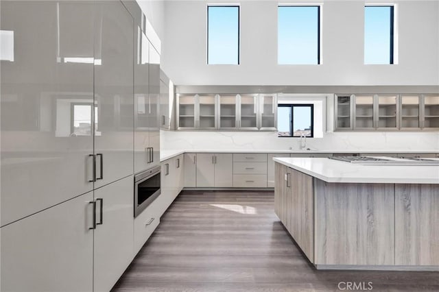 kitchen featuring tasteful backsplash, a towering ceiling, sink, and wall oven