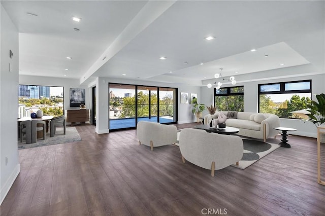 living room with a tray ceiling, dark hardwood / wood-style floors, and a notable chandelier