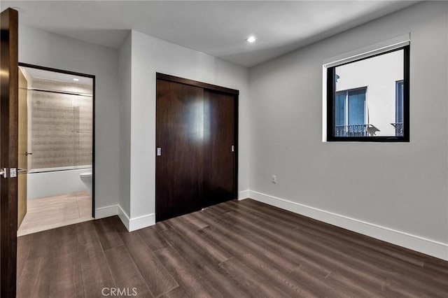 unfurnished bedroom featuring a closet and dark wood-type flooring