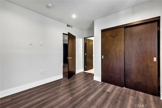 unfurnished bedroom with dark wood-type flooring and a closet