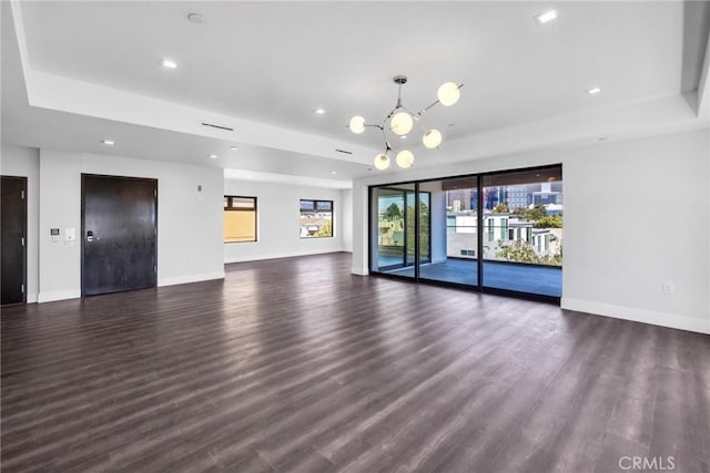 unfurnished living room featuring dark hardwood / wood-style floors, elevator, and a raised ceiling