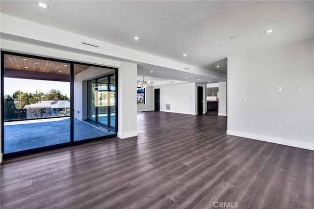 unfurnished living room with dark hardwood / wood-style floors, a chandelier, and a healthy amount of sunlight