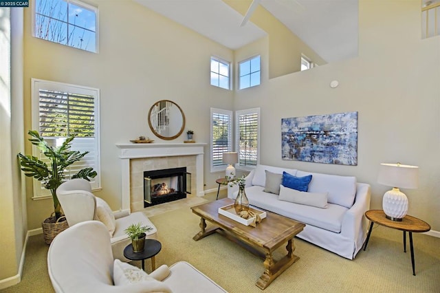 carpeted living room with a fireplace, a healthy amount of sunlight, and a high ceiling