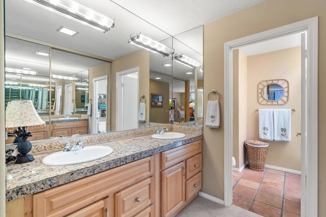 bathroom with toilet, vanity, and tile patterned floors