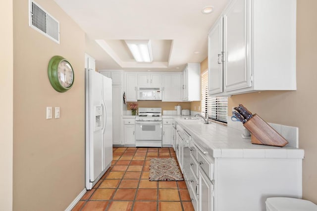 kitchen with sink, white appliances, white cabinets, and tile counters