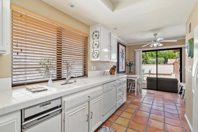 kitchen featuring tile counters, white dishwasher, tile patterned floors, white cabinets, and sink