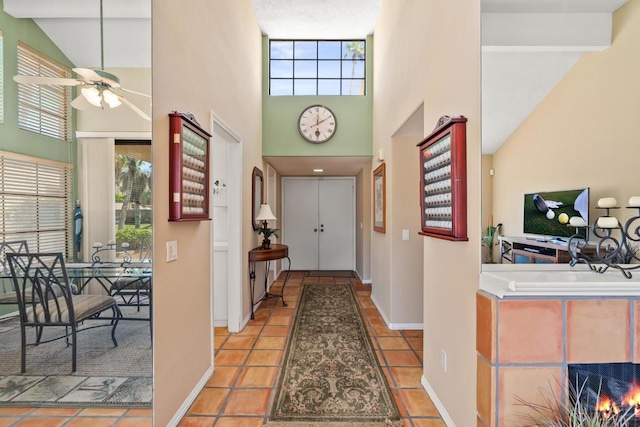 foyer entrance featuring ceiling fan, light tile patterned floors, beamed ceiling, and high vaulted ceiling