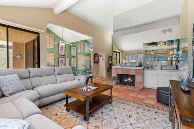 living room featuring ceiling fan, light tile patterned floors, a fireplace, and lofted ceiling with beams