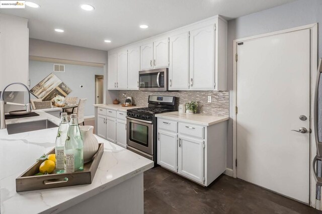 kitchen featuring light stone counters, white cabinets, appliances with stainless steel finishes, and sink