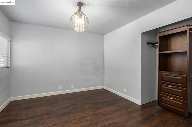 unfurnished bedroom featuring dark hardwood / wood-style floors, a closet, and a chandelier