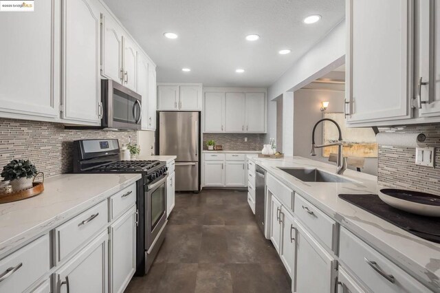 kitchen featuring light stone countertops, stainless steel appliances, white cabinets, and sink