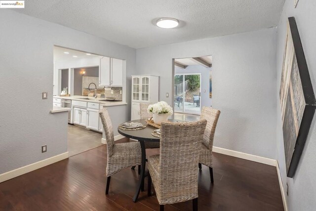 dining room with sink, a textured ceiling, and dark hardwood / wood-style floors