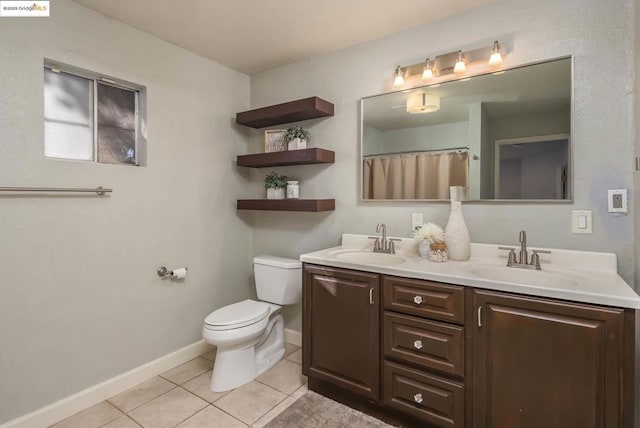 bathroom with toilet, vanity, and tile patterned floors