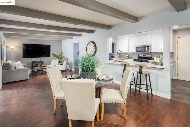 dining area with beam ceiling, dark hardwood / wood-style floors, and sink