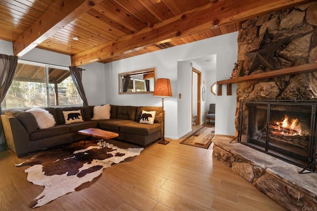 living room with a stone fireplace, beam ceiling, light hardwood / wood-style flooring, and wooden ceiling