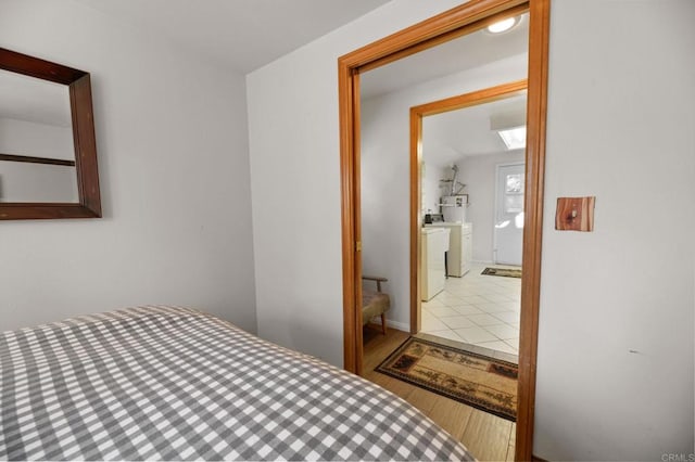 bedroom with separate washer and dryer, hardwood / wood-style floors, and ensuite bath