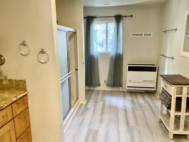 bathroom with hardwood / wood-style floors, vanity, heating unit, and an enclosed shower