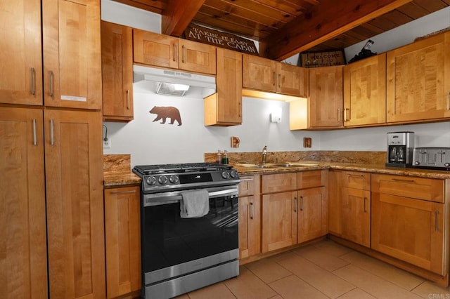 kitchen featuring sink, light stone counters, gas stove, light tile patterned flooring, and beamed ceiling