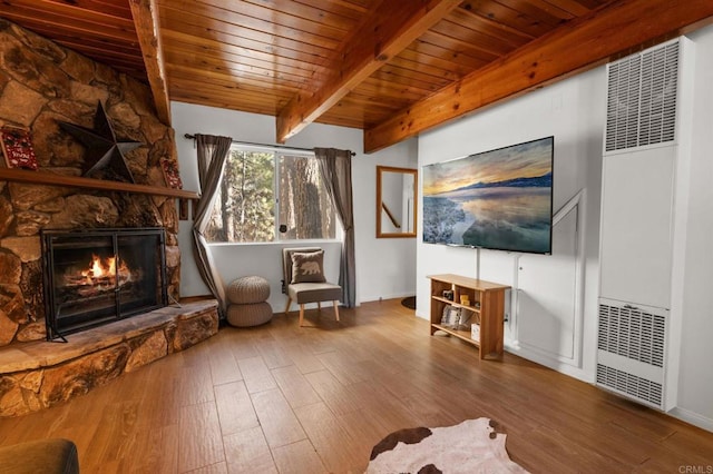 unfurnished room with beamed ceiling, wood ceiling, a stone fireplace, and wood-type flooring