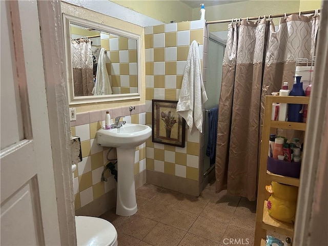 bathroom with tasteful backsplash, toilet, tile walls, sink, and a shower with shower curtain