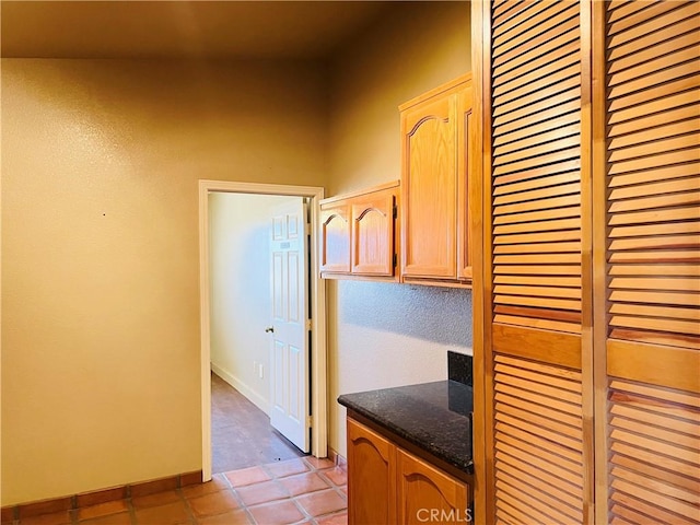 kitchen featuring light tile patterned floors, dark stone counters, and light brown cabinets