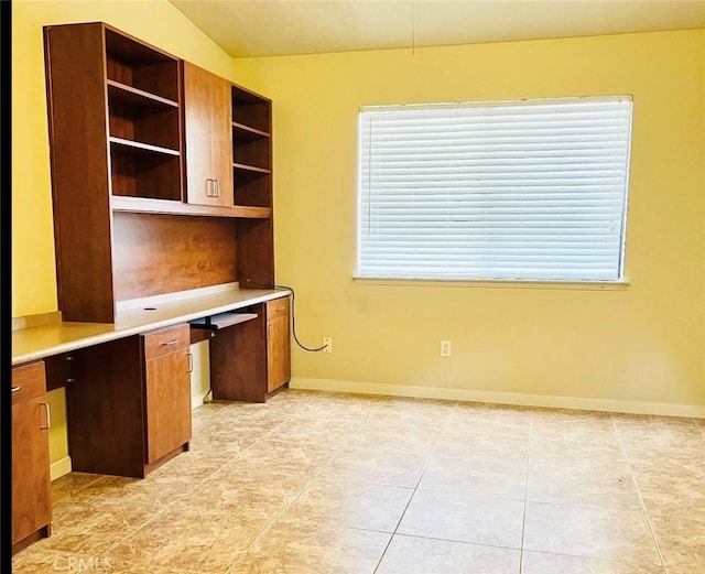 unfurnished office with built in desk, a wealth of natural light, and lofted ceiling