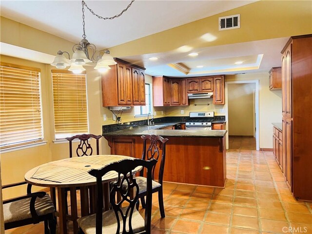 kitchen featuring sink, hanging light fixtures, a raised ceiling, a notable chandelier, and gas range