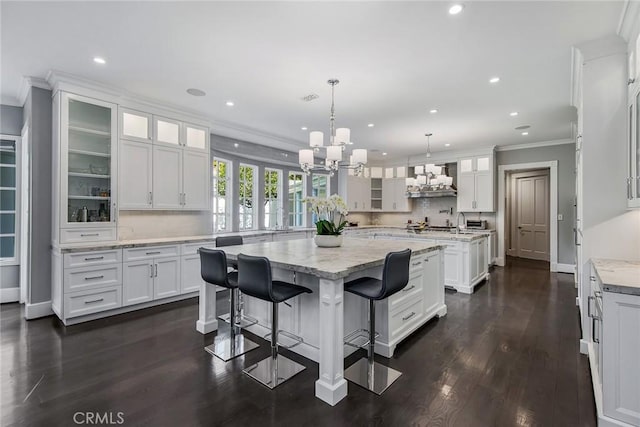 kitchen featuring backsplash, a kitchen island, pendant lighting, white cabinets, and a breakfast bar