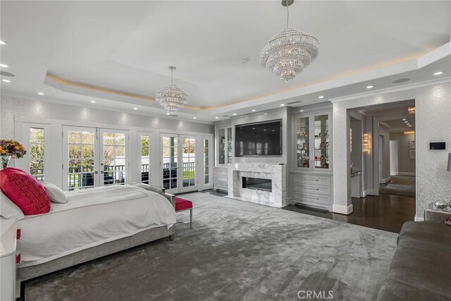 bedroom featuring an inviting chandelier, a tray ceiling, and multiple windows