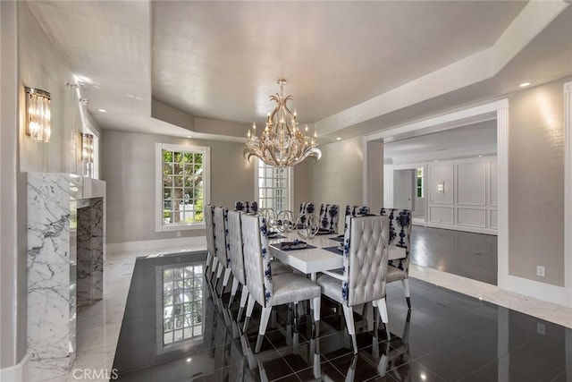 dining room featuring a chandelier, a raised ceiling, and dark tile patterned floors