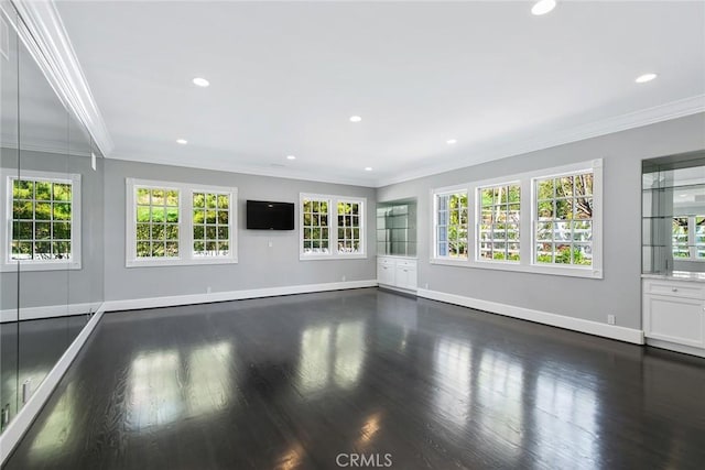 unfurnished living room with dark wood-type flooring, a wealth of natural light, and crown molding