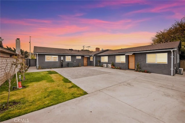 single story home featuring central air condition unit and a yard