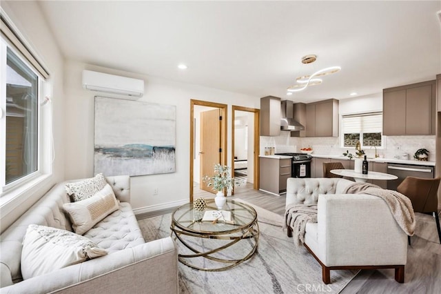 living room featuring a healthy amount of sunlight, a wall mounted AC, and light hardwood / wood-style floors