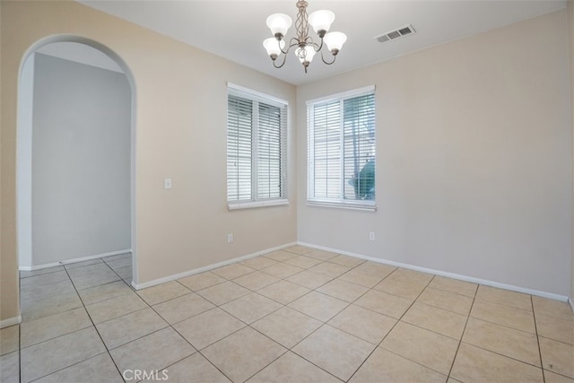 tiled spare room with a chandelier