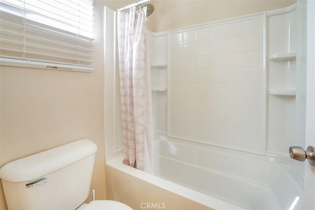 bathroom featuring toilet and shower / bath combination with curtain