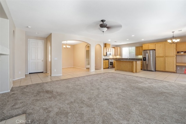 unfurnished living room with ceiling fan with notable chandelier, light colored carpet, and sink