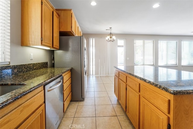 kitchen with an inviting chandelier, light tile patterned floors, dishwasher, dark stone counters, and a kitchen island