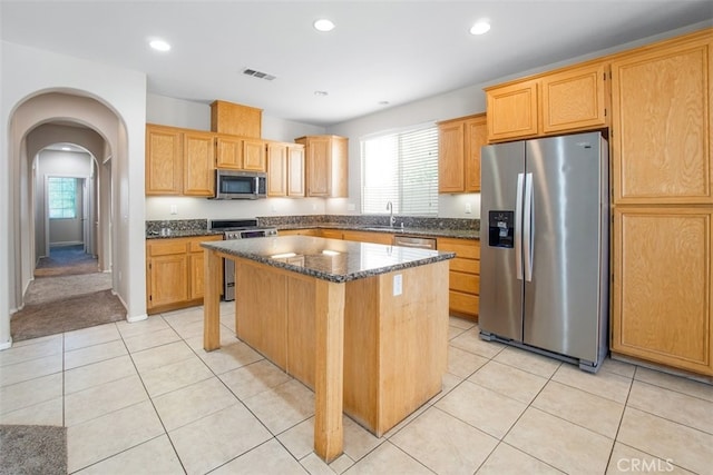 kitchen with a wealth of natural light, stainless steel appliances, a kitchen island, and sink