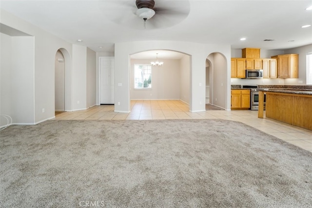 unfurnished living room featuring light carpet and ceiling fan with notable chandelier