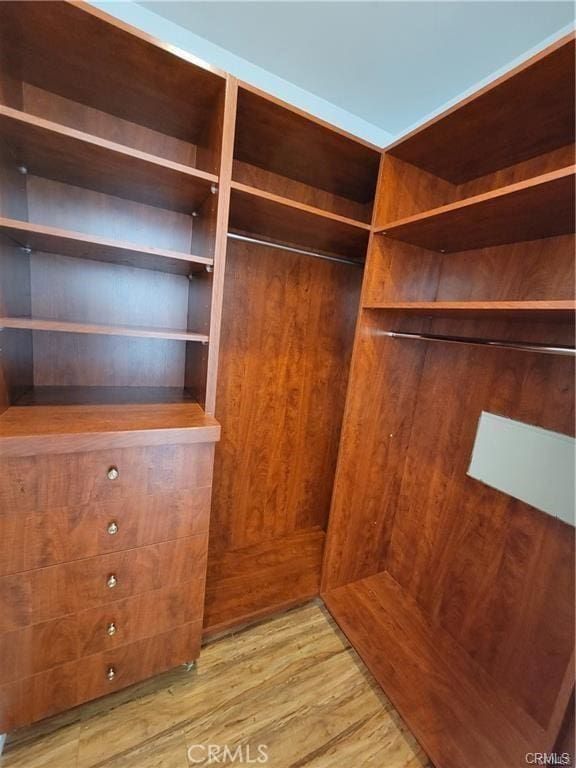 walk in closet with light hardwood / wood-style flooring