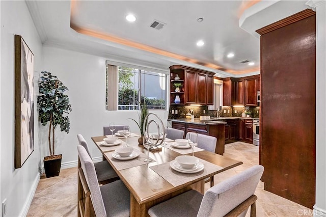 tiled dining area with crown molding, a tray ceiling, and sink