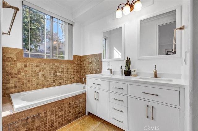 bathroom with tile patterned flooring, tiled tub, and vanity